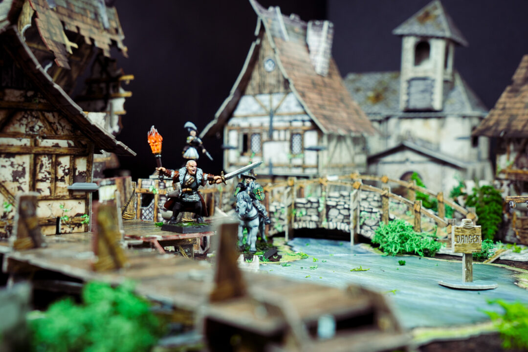 Mordheim terrain with river defended by a witch hunter and a freelance knight